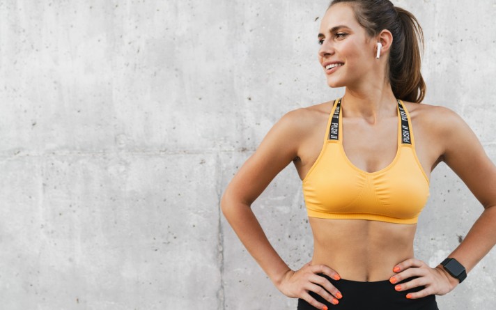 women in yellow gym top standing against grey wall