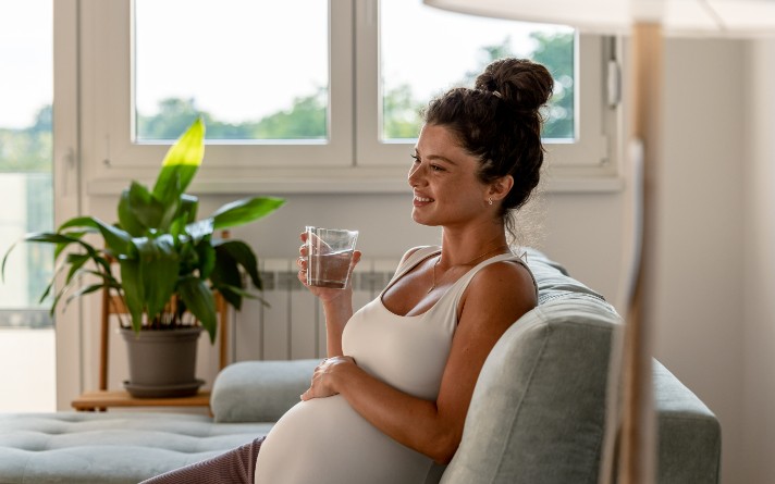 pregnant woman in white tank top sitting on couch