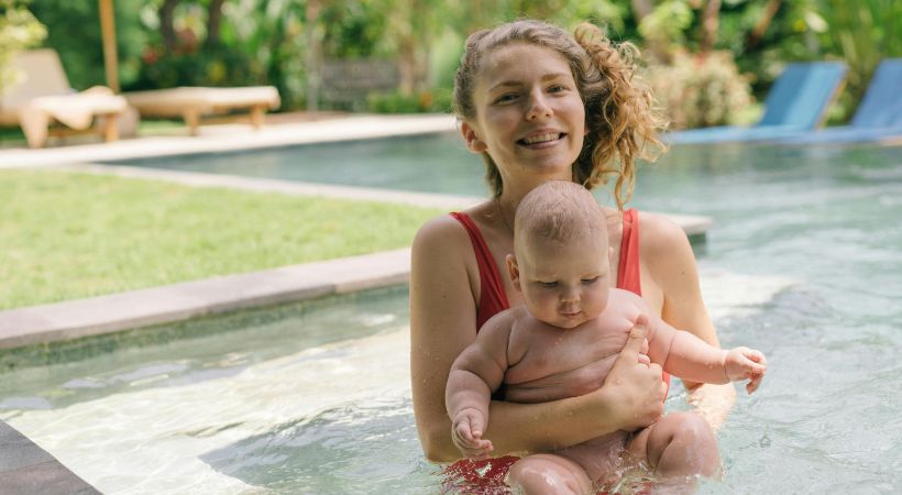 A mother swimming with her a baby