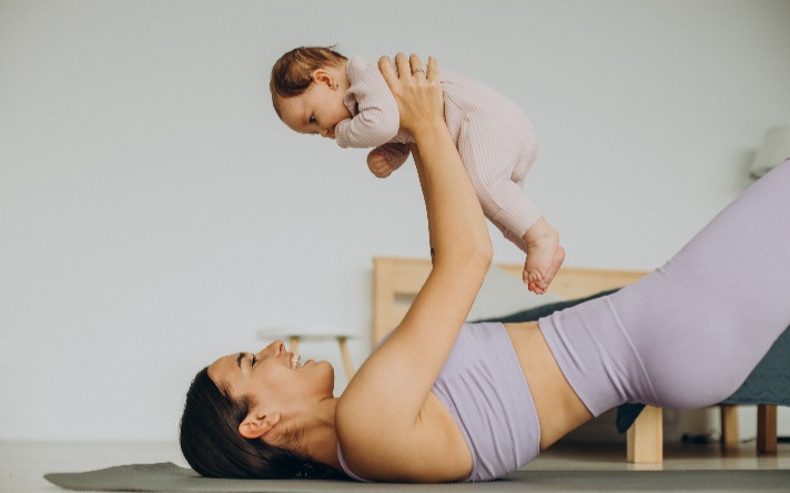 New mother exercising while holding up baby.